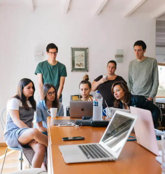 Team gathered around laptops in a meeting