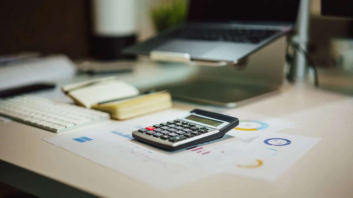 Laptop, calculator and documents for budgeting an AI automation project