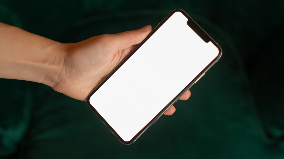 Hand holding a smartphone with a blank screen, ready for a new app design