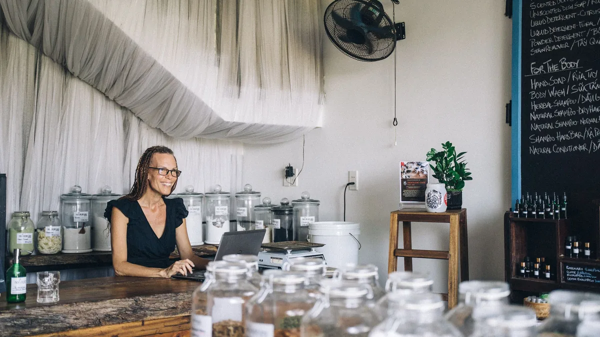 Small business owner working on a laptop in her shop, exploring AI tools